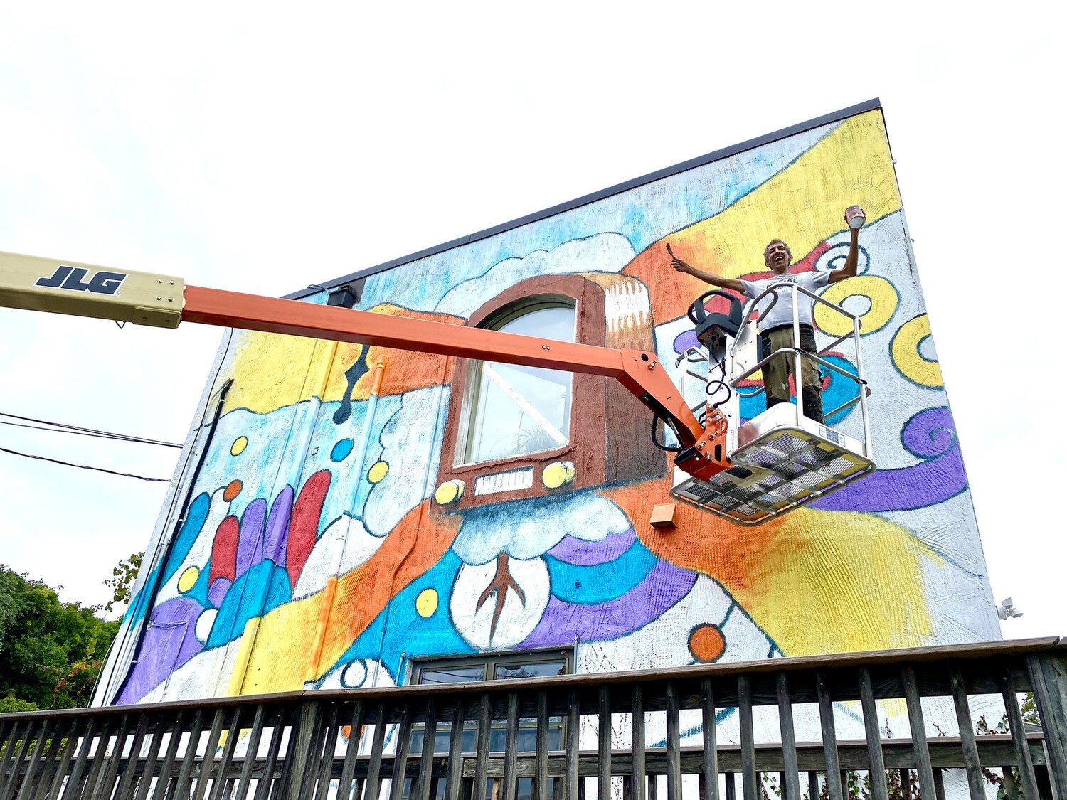 Chicho on a cherry picker painting the WTJU Mural.
