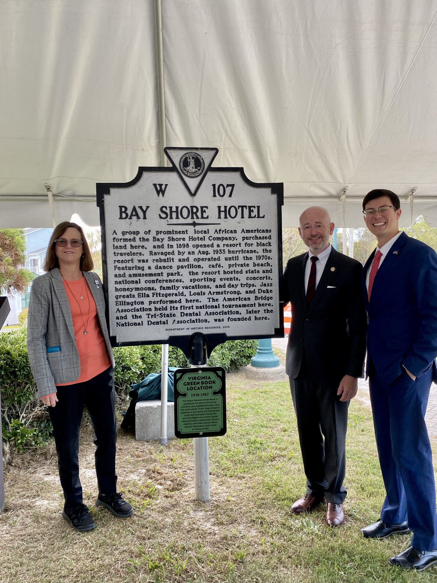 Historic Marker commemorating the Bay Shore Hotel. Left to Right:   Susan Hellman, Architectural Historian, Alexandria, Virginia; Delegate Michael Mullin (D – Newport News); and Mullin&apos;s Chief of Staff at the time, Randy Riffle.  Inscription:  A group of prominent local African Americans formed the Bay Shore Hotel Company, purchased land here, and in 1898 opened a resort for black travelers. Ravaged by an Aug. 1933 hurricane, the resort was rebuilt and operated until the 1970s. Featuring a dance pavilion, café, private beach, and an amusement park, the resort hosted state and national conferences, sporting events, concerts, honeymoons, family vacations, and day trips. Jazz greats Ella Fitzgerald, Louis Armstrong, and Duke Ellington performed here. The American Bridge Association held its first national tournament here, and the Tri-State Dental Association, later the National Dental Association, was founded here.